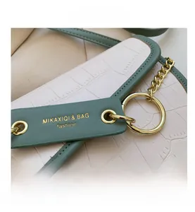 Detail of embossed crocodile leather texture and gold hardware on two-tone saddle bag