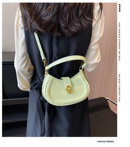Detail of mint green crescent bag with golden hardware shown worn by a model