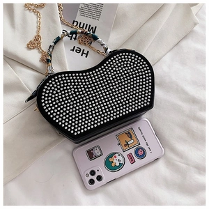 Detail of heart-shaped rhinestone handbag with decorative scarf handle and gold chain