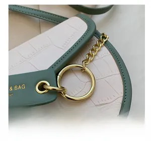 Detail of sage green and pink crocodile texture leather with gold hardware rings