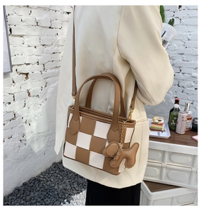 Détail du sac seau à damier avec charm chien présenté dans un cadre de vie décontracté