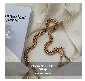 Gros plan détaillé d'une bandoulière en chaîne dorée déposée sur une veste de blazer blanc
