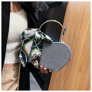 Detail of heart-shaped handbag with silver studs, gold ring handle and silk scarf