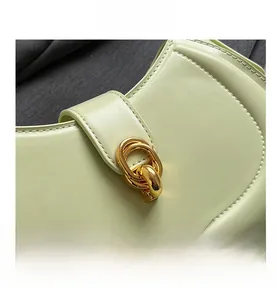 Close-up of pistachio green handbag with golden interlocking ring lock and stitching