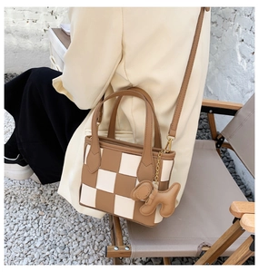 Détail du sac seau tressé avec charm chiot marron et bandoulière amovible