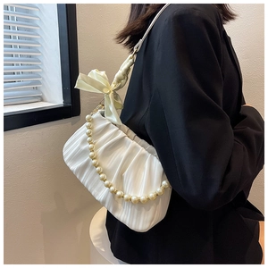 Détail du sac plissé blanc avec grand nœud jaune et chaîne de perles élégante