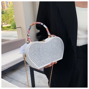 Detail view of heart-shaped white clutch bag with rhinestones and silk-wrapped handle