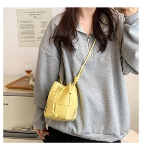Close-up of yellow woven bucket bag with leather texture and drawstring closure detail