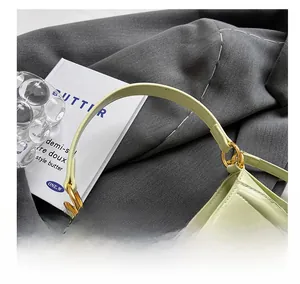 Detailed close-up of light green leather handbag handle with gold ring hardware and stitching