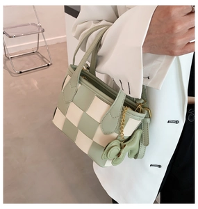 Détail du sac cabas tressé à damier vert avec pendentif chiot mignon et chaîne dorée