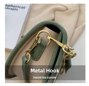 Detail of sage green and cream saddle bag with premium gold-tone hardware hook