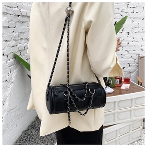 Detail of black cylindrical crossbody bag with woven texture and chain strap