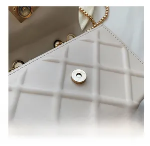 Gros plan détaillé du fermoir magnétique d'un sac à bandoulière en cuir beige matelassé