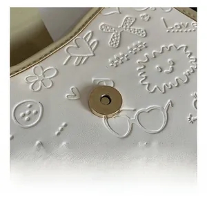 Detail of white lychee texture leather bag with embossed patterns and magnetic closure