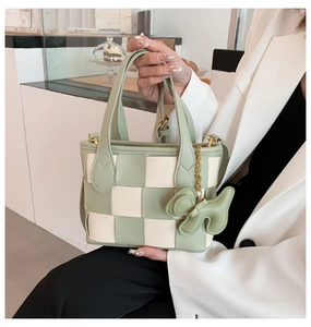 Détail du sac seau tressé vert et crème avec un charmant pendentif en forme de chiot