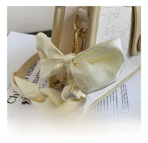 Detail of cream shoulder bag with embossed patterns and large satin bow decoration