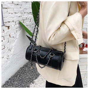 Close-up of a black woven cylinder crossbody bag with chunky silver chain detail