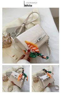 Detail of white embossed crossbody bag with cartoon patterns and decorative silk scarf