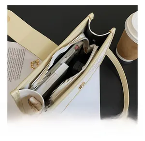 Detail view of the cream shoulder bag interior capacity with zip compartment and phone