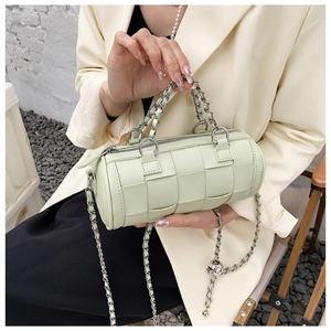 Close-up of a cylinder crossbody bag in avocado green leather with woven texture