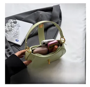 Internal capacity of the sage green crescent handbag showing phone, wallet, and lipstick