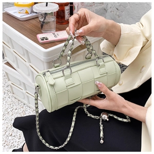 Detail of mint green woven cylinder bag with chunky chain handle and leather strap
