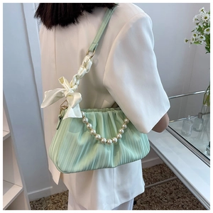 Détail du sac plissé vert menthe avec chaîne en perles et nœud en satin crème