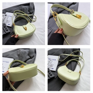 Detail view of a pale green crescent bag with golden metal knot and smooth leather finish