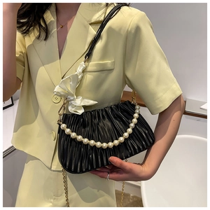 Détail du sac nuage froncé noir avec chaîne de perles et nœud en soie sur blazer