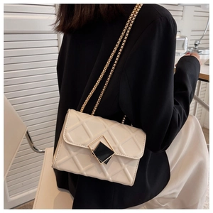 Sac bandoulière blanc matelassé avec chaîne dorée et fermoir carré sur costume noir