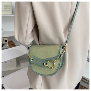 Detailed view of light green saddle bag with faux crocodile pattern and gold hardware