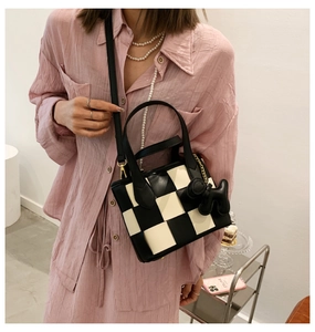 Détail du sac seau à damier noir et blanc avec bandoulière amovible et pendentif chien