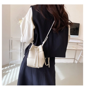 Detailed view of hand-woven beige bucket bag with drawstring closure on shoulder strap