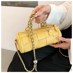 Detail of yellow woven barrel bag featuring silver chain strap and metallic ball charm