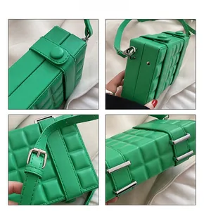 Detail view of a green plaid box bag with quilted texture and silver buckle accents