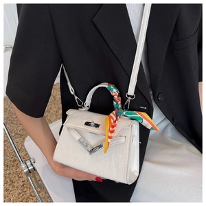 Detailed view of white embossed Kelly bag with printed silk scarf on black blazer outfit