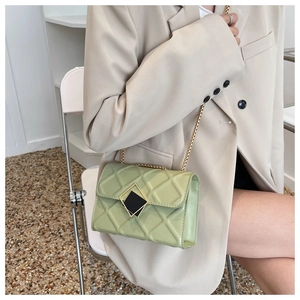 Détail du sac matelassé vert clair avec chaîne dorée sur un costume beige élégant
