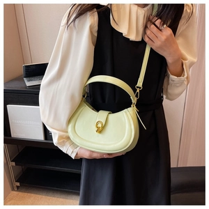 Detail of light green semi-circle crossbody bag with gold ring buckle on model