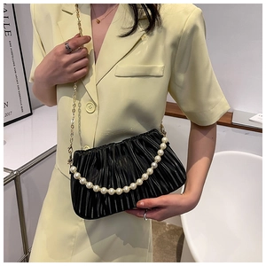Détail du sac nuage plissé noir avec poignée en perles et chaîne dorée sur modèle