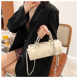 Detail of cream woven cylinder bag with silver chain strap and metal ball charm decoration