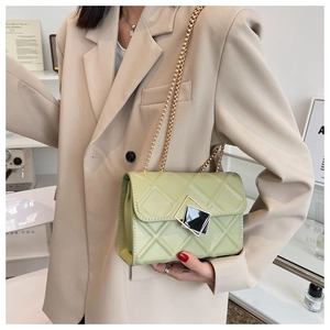 Détail d'un sac matelassé vert clair avec fermoir géométrique sur un blazer beige chic