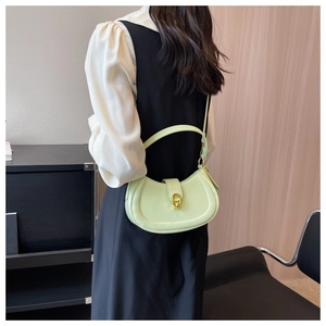 Model wearing a mint green half-moon crossbody bag with a gold metal twist lock buckle