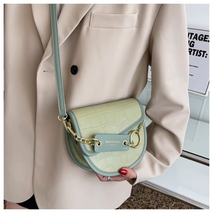 Detail of sage green crocodile pattern saddle bag with gold chain and leather strap