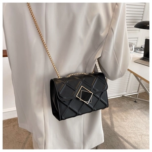 Détail du sac à bandoulière matelassé noir avec boucles dorées et bandoulière chaîne