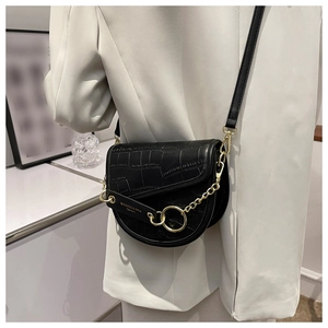 Detail of black crocodile pattern saddle bag featuring gold chain and crossbody strap