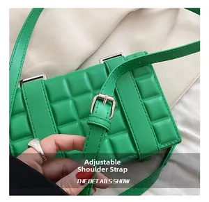 Close-up of the adjustable shoulder strap and silver hardware on a green plaid crossbody bag