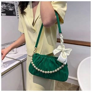 Détail du sac en satin plissé vert avec de grandes perles blanches et nœud en soie
