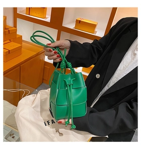 Detail of green woven bucket bag showing modular texture and drawstring closure
