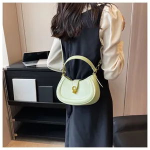 Detail of light green crescent handbag featuring a gold U-shaped metal clasp and leather strap