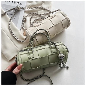 Detail of woven cylinder bags in cream and mint with thick metal chains and ball charms